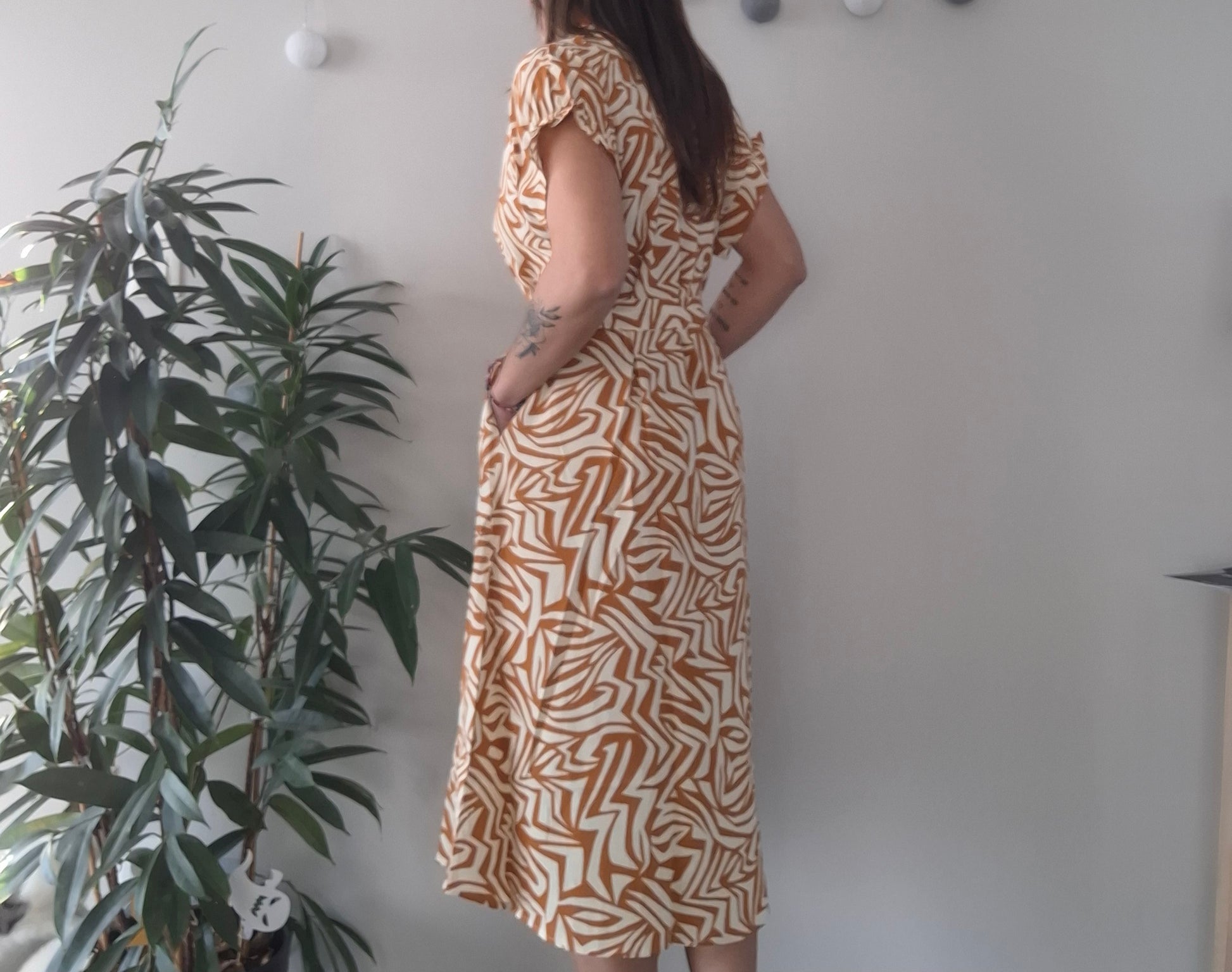 Woman in yellow geometric midi dress standing indoors near a plant, Le Petit Placard fashion