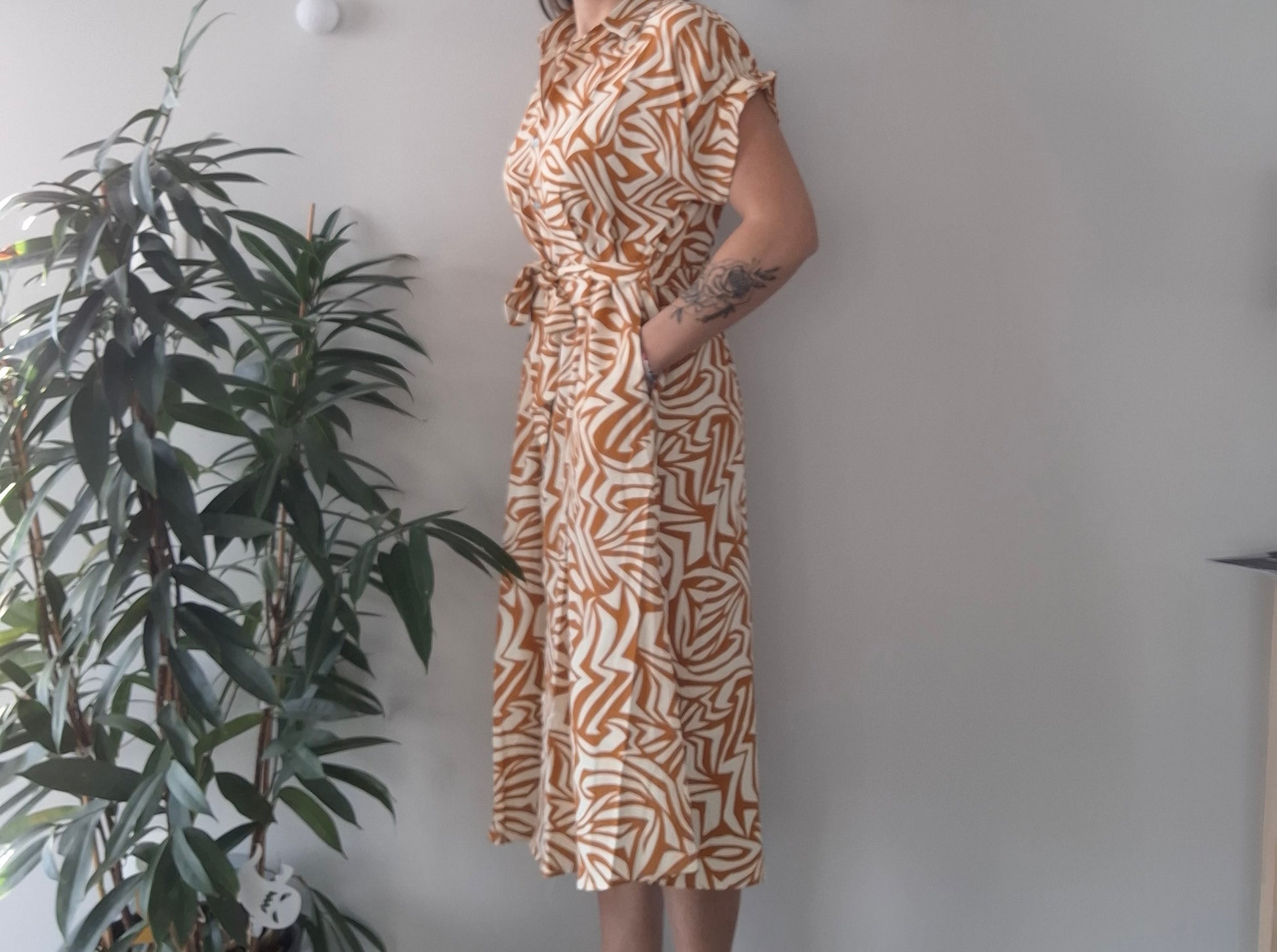 Woman in geometric print midi dress with belt, Le Petit Placard fashion, indoor plant decor