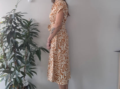 Woman in geometric print dress standing by green plant, Le Petit Placard fashion accessory decor
