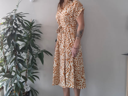 Woman in geometric print dress standing by a plant, modern and trendy style from Le Petit Placard