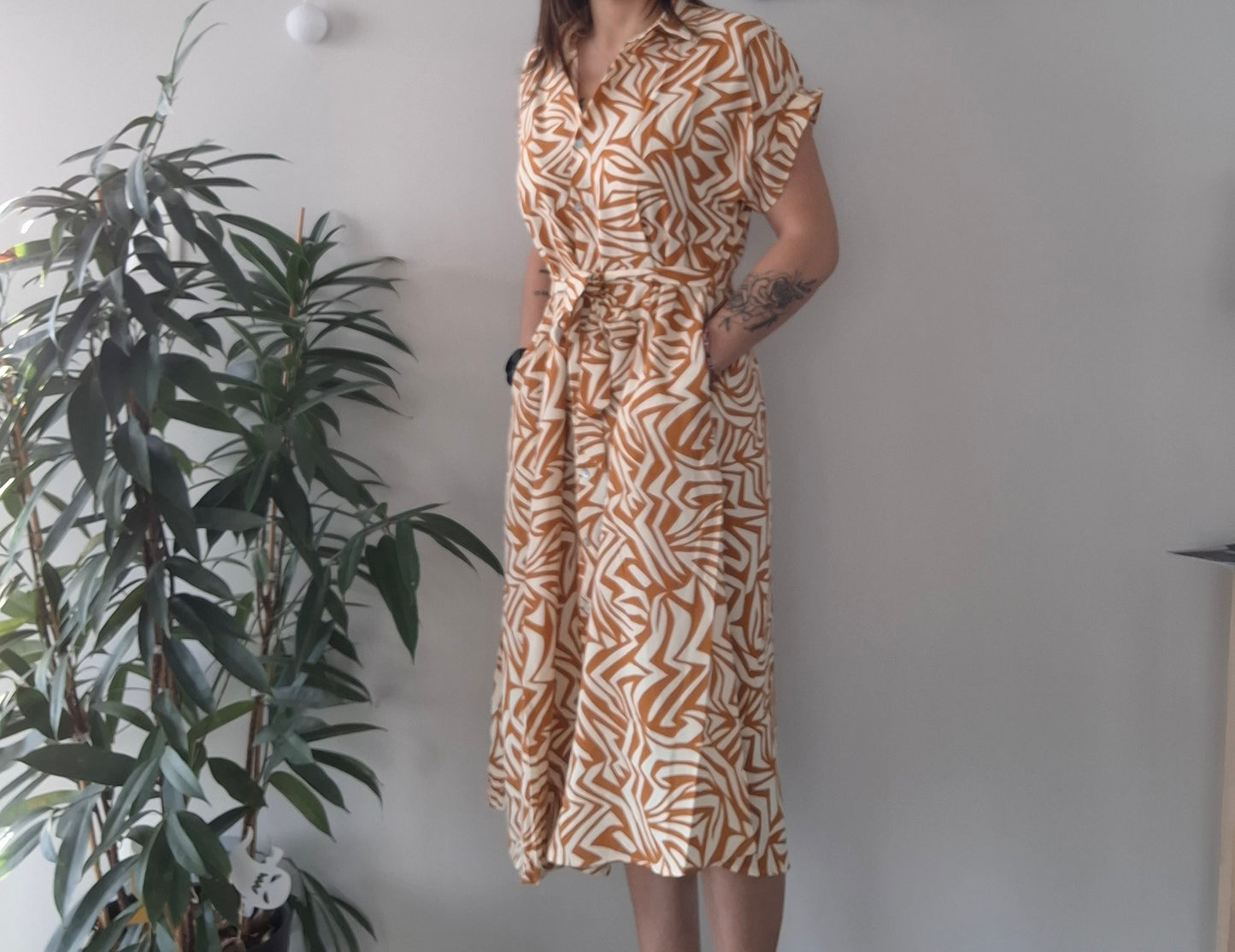 Woman in orange and white patterned midi dress, Le Petit Placard fashion, standing indoors