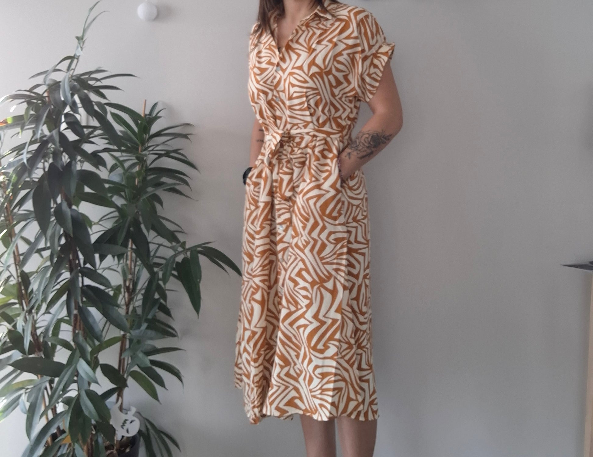 Woman in orange and white patterned midi dress, Le Petit Placard fashion, standing indoors