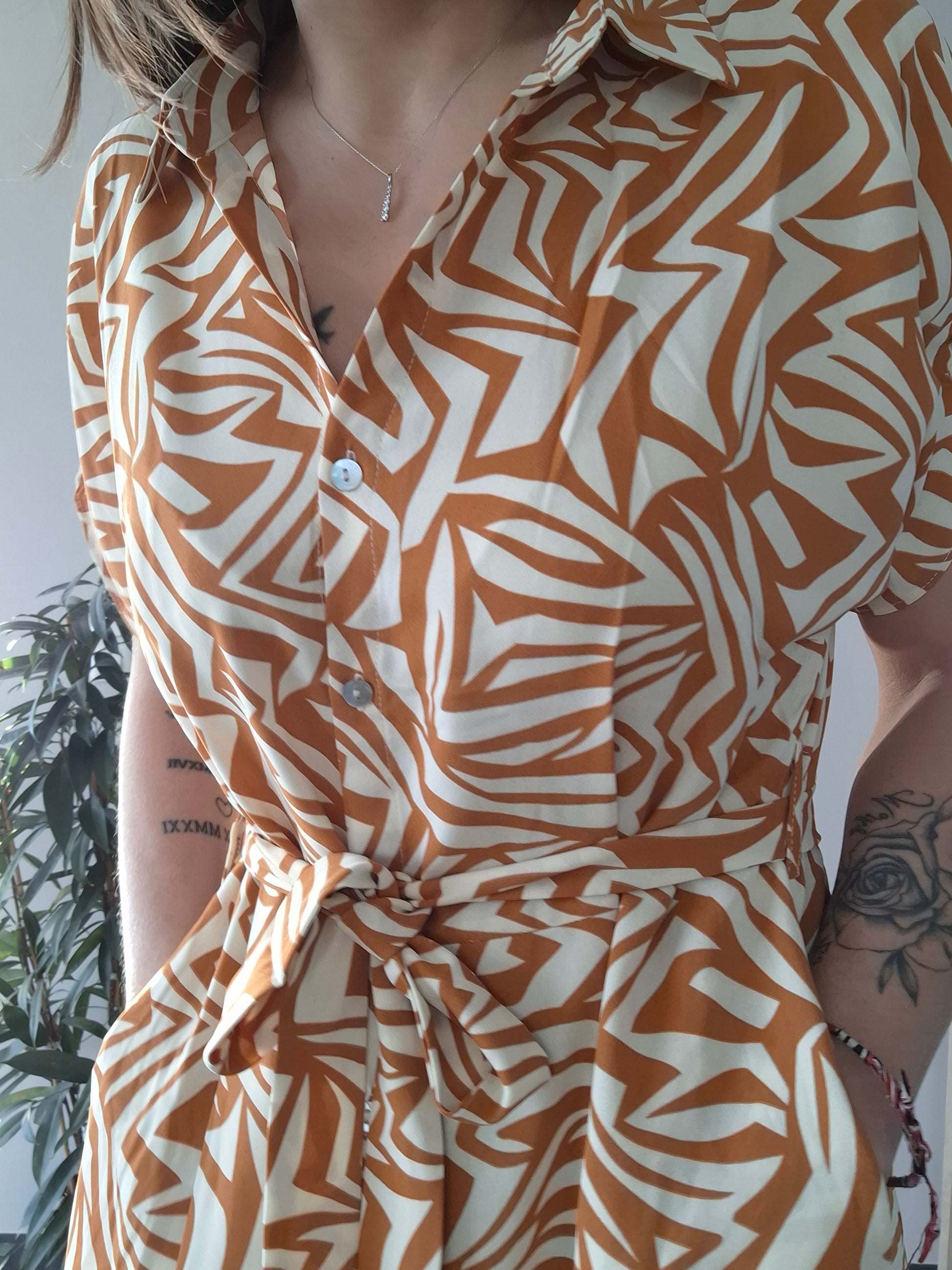 Woman wearing an orange and white geometric print belted dress from Le Petit Placard