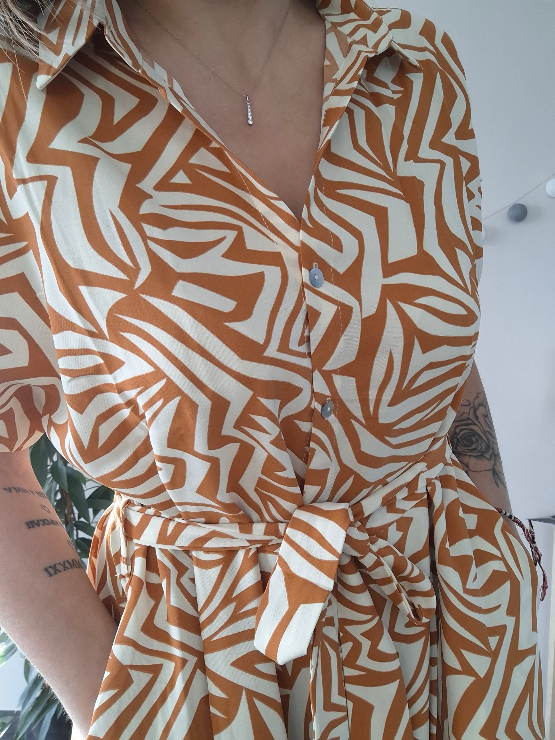 Woman wearing an orange and white patterned belted dress from Le Petit Placard