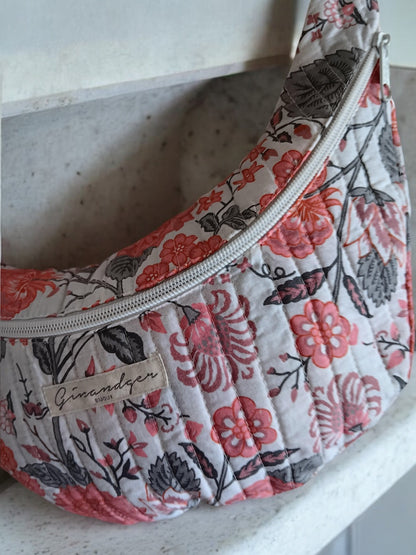 Quilted floral print bum bag with pink and gray flowers, displayed on a white surface.