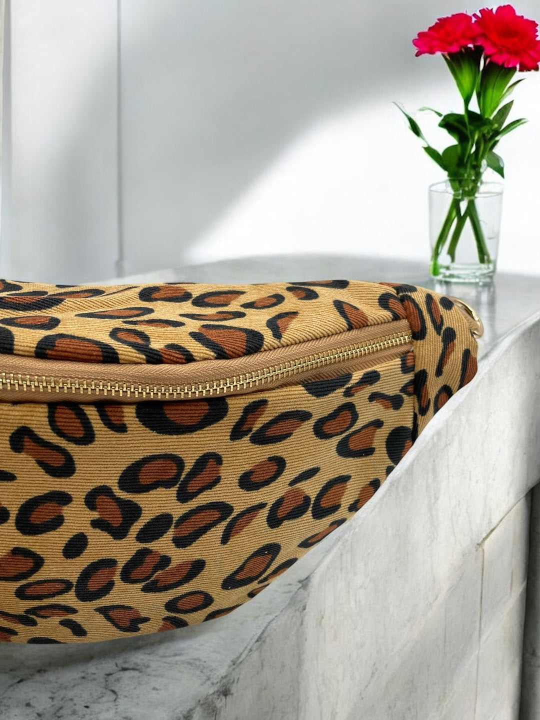 Sac banane coton épais camel léopard avec fermeture éclair dorée, posé sur une surface en marbre