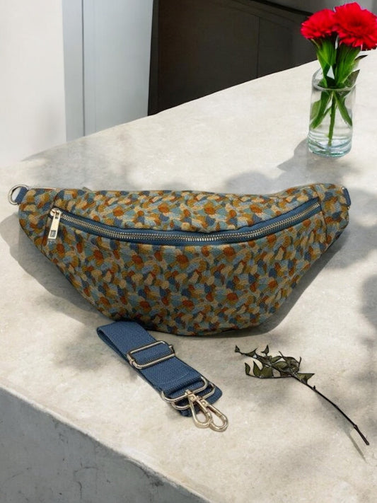 Sac banane coton épais velours fin bleu et jaune avec motifs, bandoulière bleue et fermoir doré sur marbre blanc