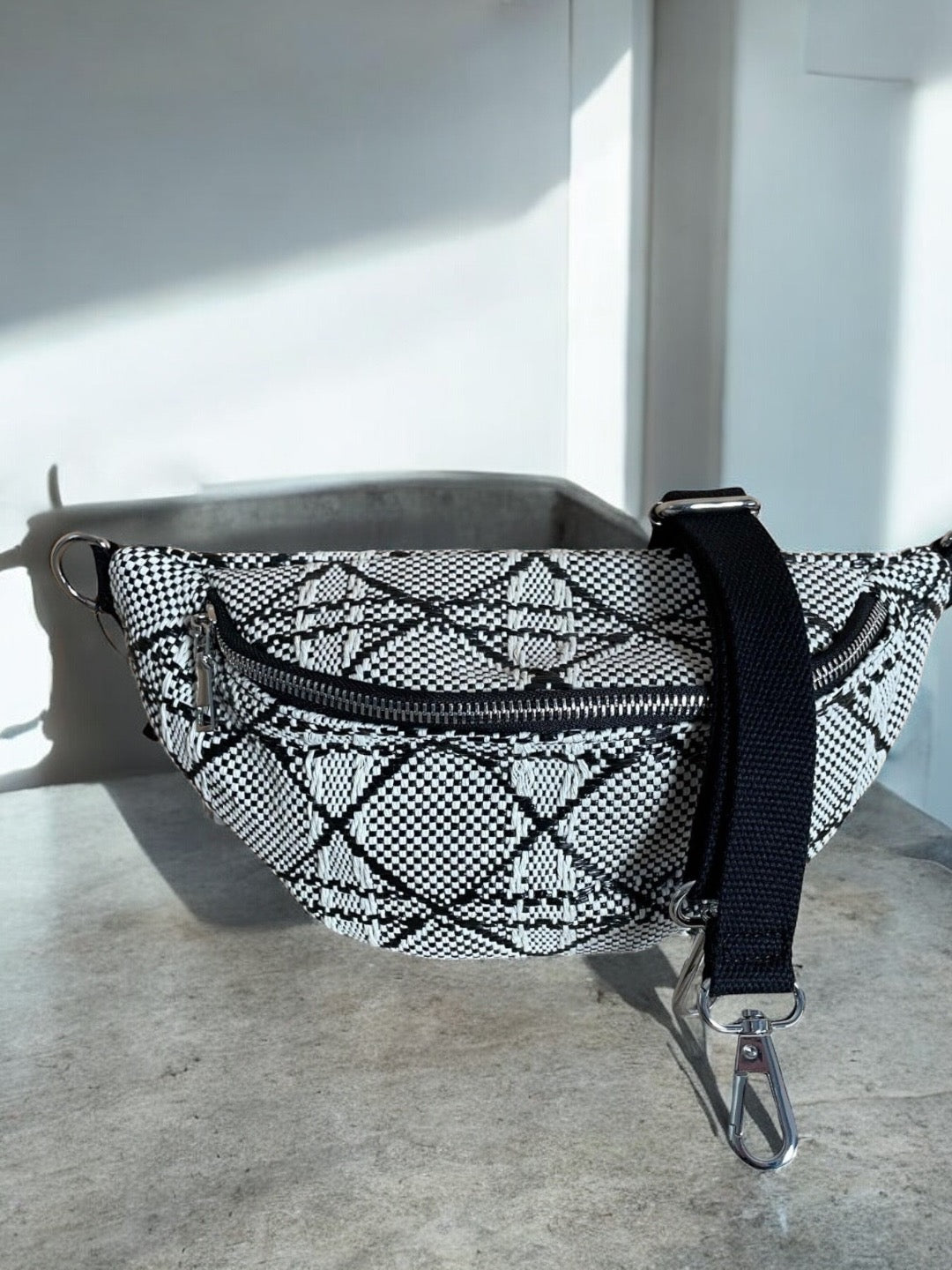 Sac banane effet tissu tressé noir et blanc avec motifs géométriques, fermeture éclair et bandoulière noire