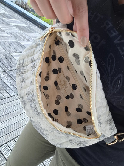 Sac banane en coton matelassé, motif liberty blanc avec fleurs gris et poche intérieure à pois noirs.