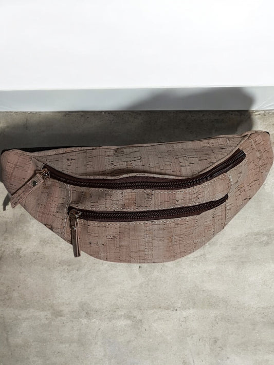 Brown textured cork belt bag with two zip pockets on a concrete floor, Le Petit Placard accessory