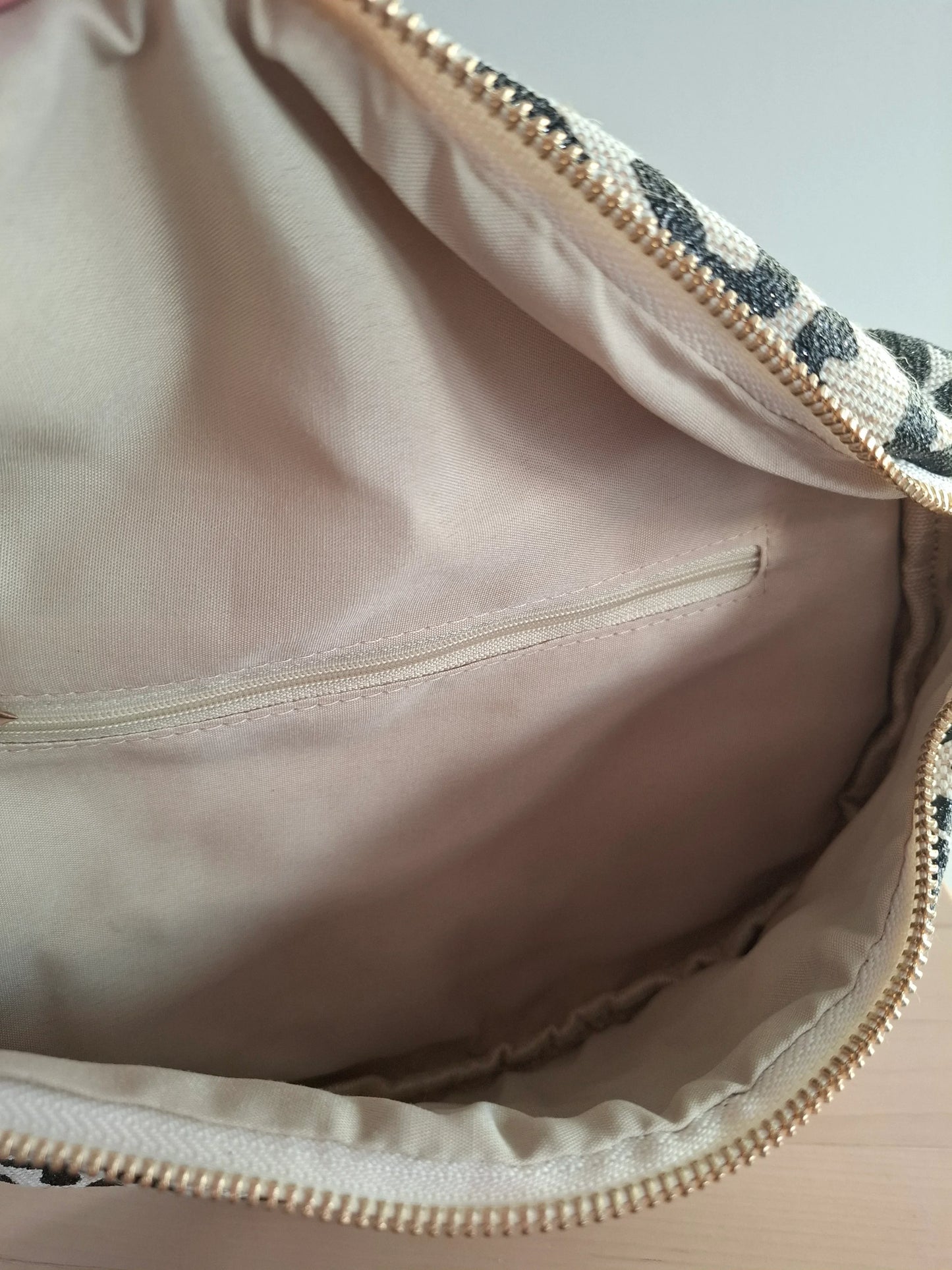 Intérieur du sac banane motif léopard noir et beige avec poche zippée dorée et doublure rose pâle