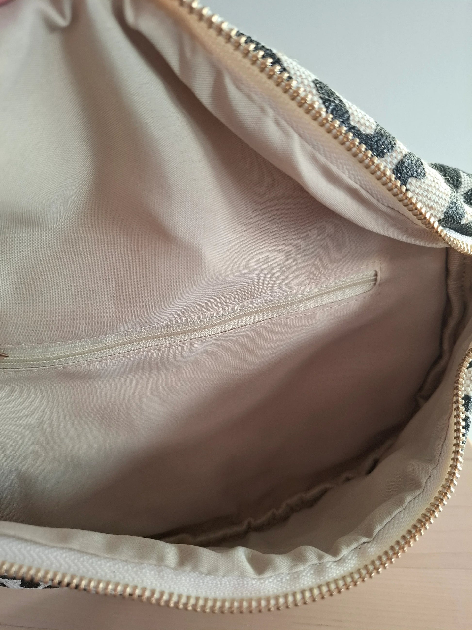 Intérieur du sac banane motif léopard noir et beige avec poche zippée dorée et doublure rose pâle