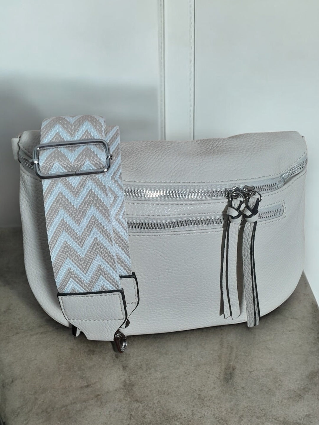 Trendy white leather sac banane with zigzag strap on concrete, Le Petit Placard accessory