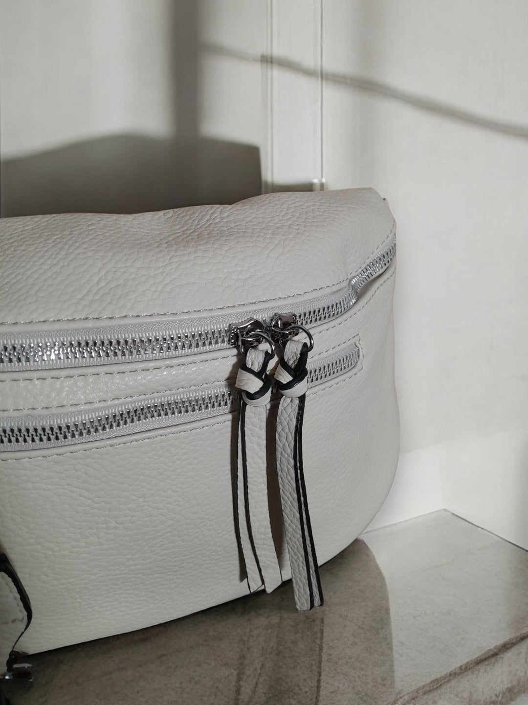 Close-up of a white leather bum bag with silver zippers, Le Petit Placard accessory