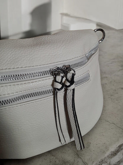 White faux leather bum bag with silver zippers from Le Petit Placard on stone surface