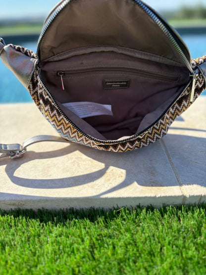 Open chevron-patterned sac banane with interior pocket, photographed outdoors by a pool
