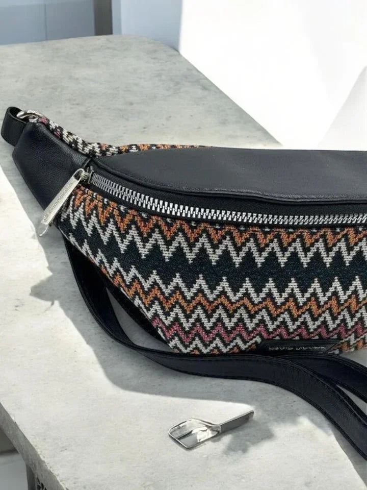 Patterned zigzag fabric and black leather belt bag on table, trendy accessory at Le Petit Placard