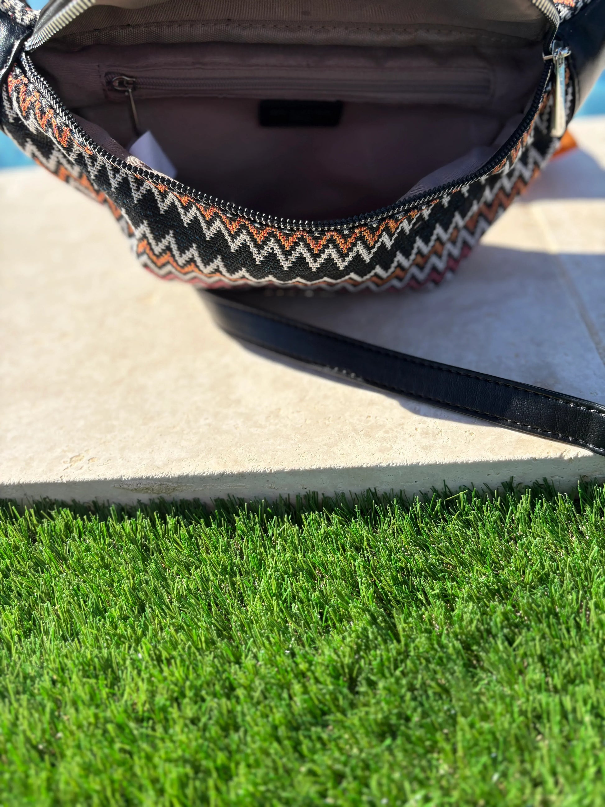 Open zigzag-patterned sac banane on a stone surface above green grass, Le Petit Placard accessories
