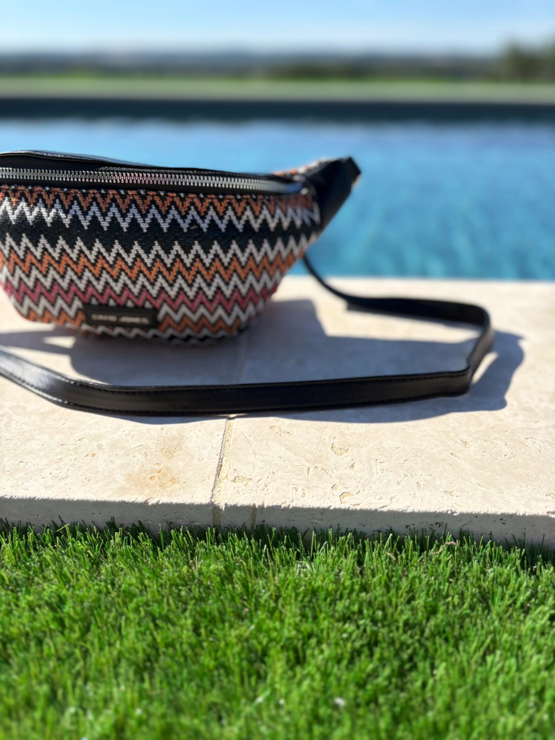 Patterned sac banane by a poolside, trendy accessory at Le Petit Placard.