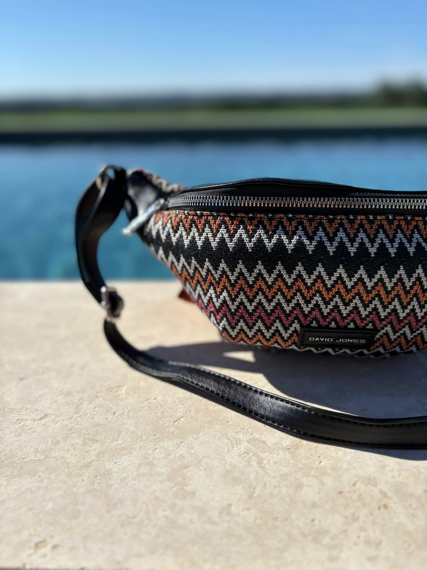 David Jones zigzag patterned sac banane on stone surface by water, trendy accessory Le Petit Placard