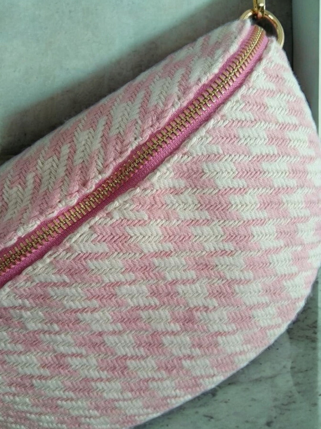 Pink and white woven fabric fanny pack with gold zipper, trendy accessory at Le Petit Placard