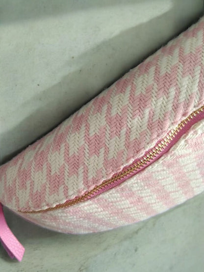 Pink and white houndstooth patterned sac banane with gold zipper on light background