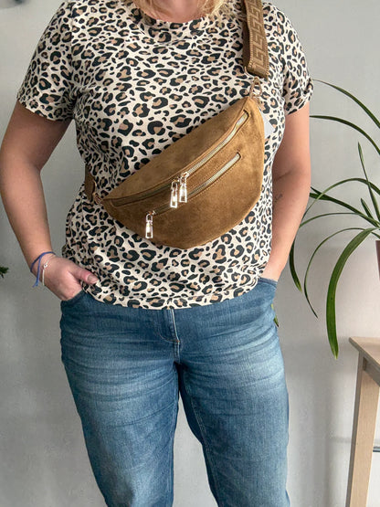 Sac banane toucher daim camel porté en bandoulière, 2 poches zip doré et sangle fantaisie, sur tenue léopard et jean