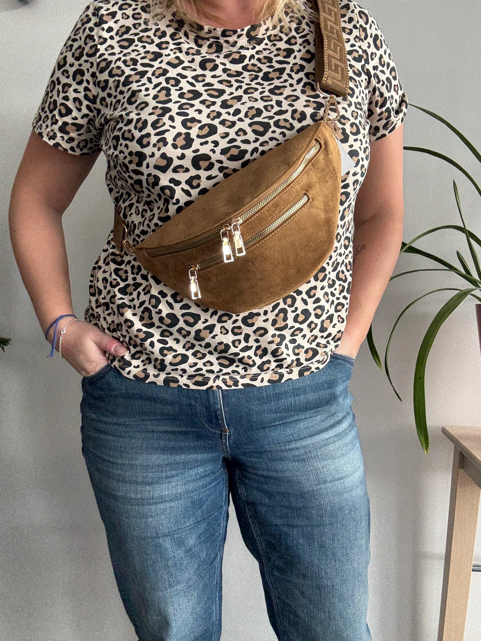 Sac banane toucher daim camel porté en bandoulière, 2 poches zip doré et sangle fantaisie, sur tenue léopard et jean