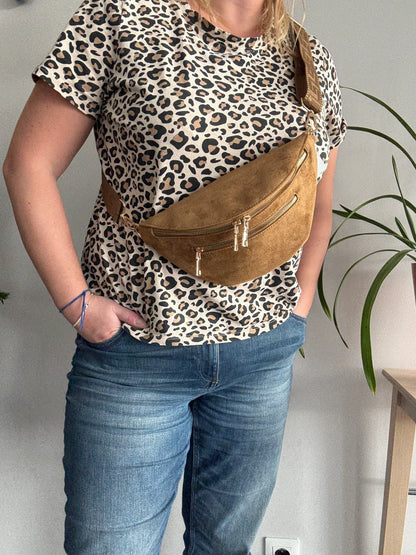 Sac banane toucher daim camel porté en bandoulière avec 2 poches zip doré sur t-shirt léopard et jean