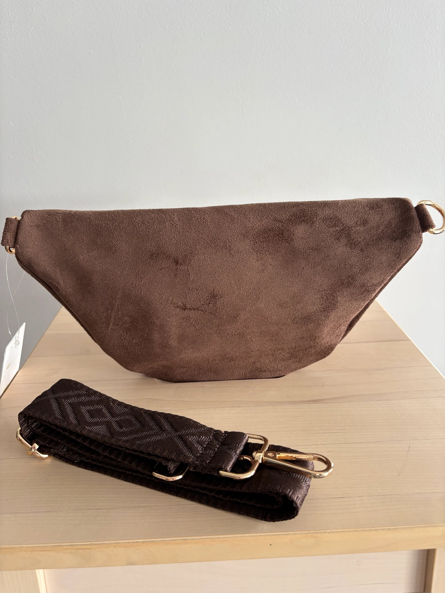 Sac banane toucher daim marron chocolat avec bandoulière et détails dorés, posé sur une table en bois