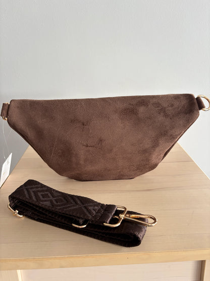 Sac banane toucher daim marron chocolat avec bandoulière et détails dorés, posé sur une table en bois