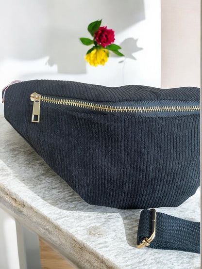 Black corduroy fanny pack with gold zipper on marble surface at Le Petit Placard accessories shop