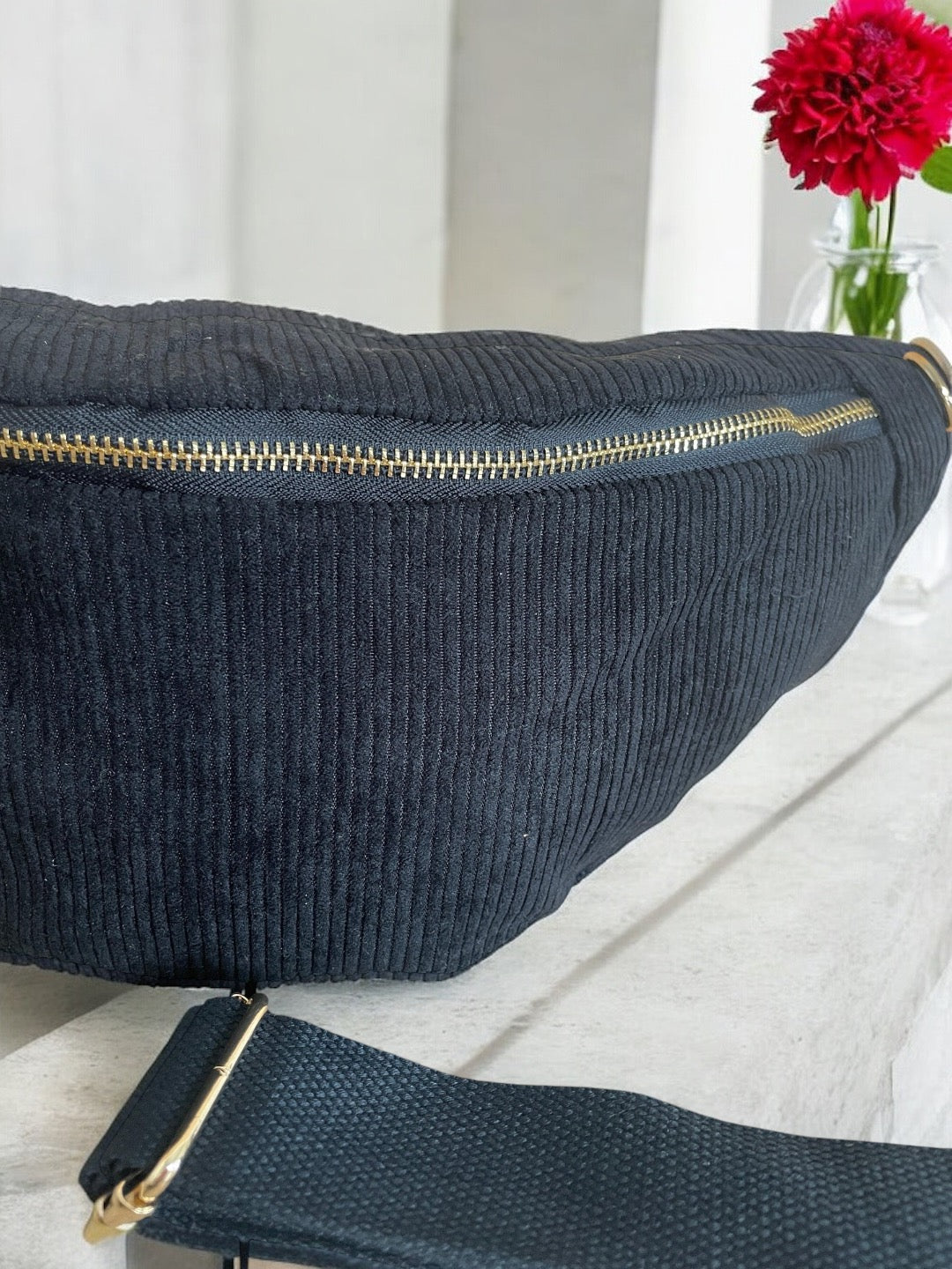 Black corduroy bum bag with gold zipper, Le Petit Placard accessory, on stone surface