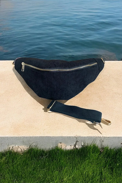 Black corduroy belt bag with gold zipper by the water, trendy accessory from Le Petit Placard