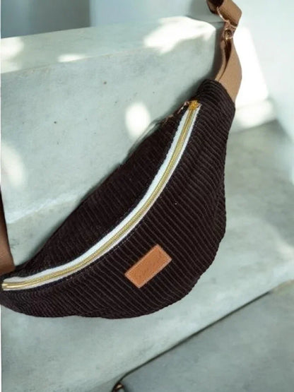 Brown corduroy bum bag with beige strap and zipper, displayed on a concrete step, Le Petit Placard