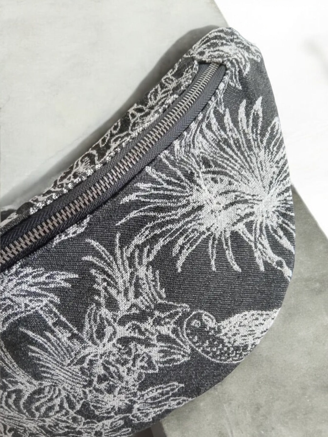 Close-up of a fabric belt bag with white tropical print, trendy accessory at Le Petit Placard