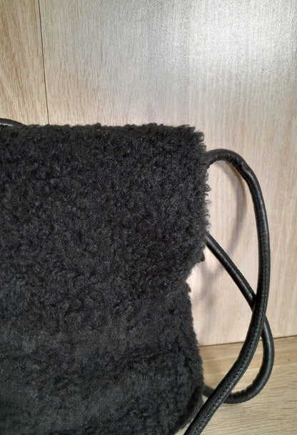 Black faux fur crossbody bag with leather strap on wood background, Le Petit Placard accessory