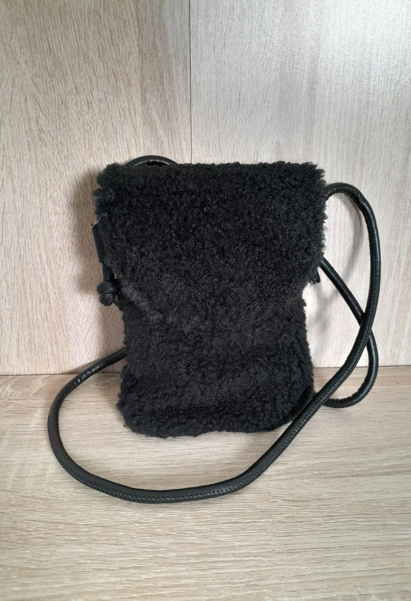 Small black faux fur crossbody pouch bag with long strap on wooden surface, Le Petit Placard