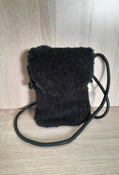 Small black faux fur crossbody pouch bag with long strap on wooden surface, Le Petit Placard