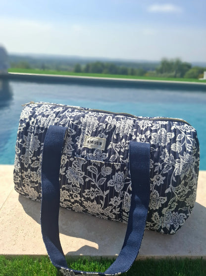 Sac polochon en coton matelassé Liberty floral Toile de Jouy bleu marine et blanc, posé au bord d'une piscine
