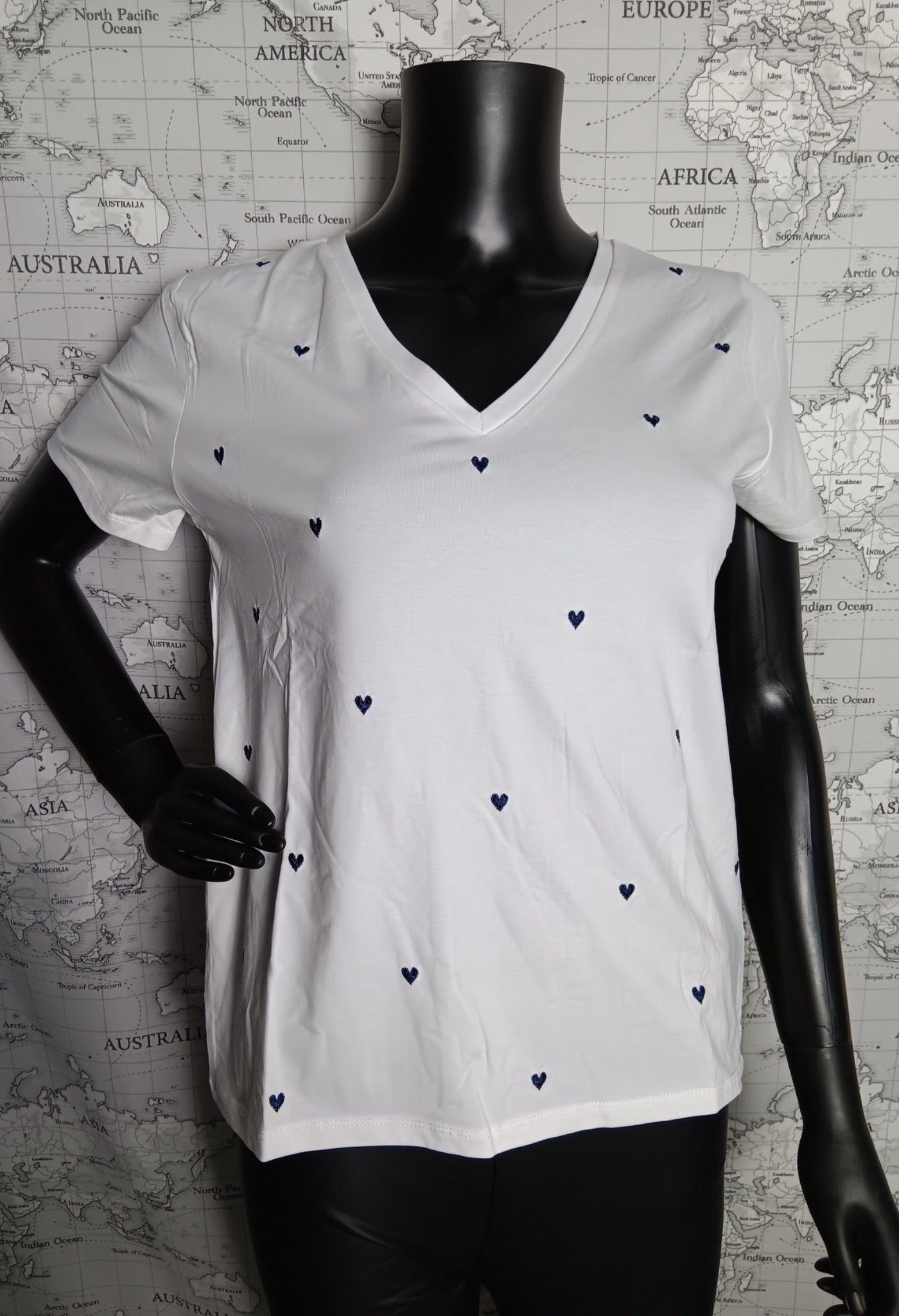 T-shirt blanc à col en V avec petits cœurs bleus brodés dispersés sur tout le vêtement.