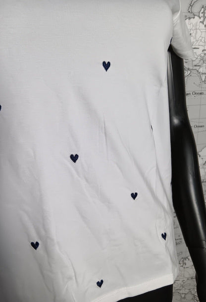T-shirt blanc avec petits cœurs bleus brodés, visible sur mannequin noir.