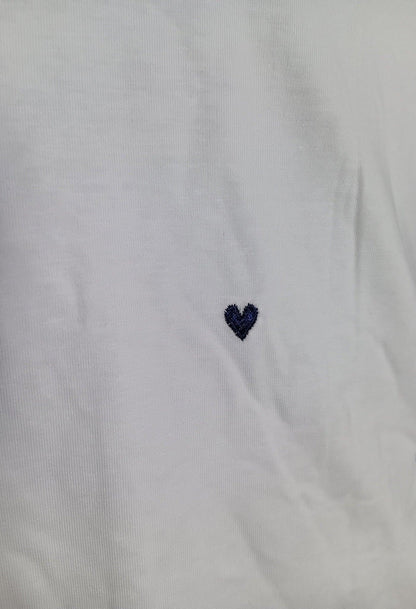 Petit T-shirt blanc avec un petit cœur brodé bleu marine sur la poitrine.