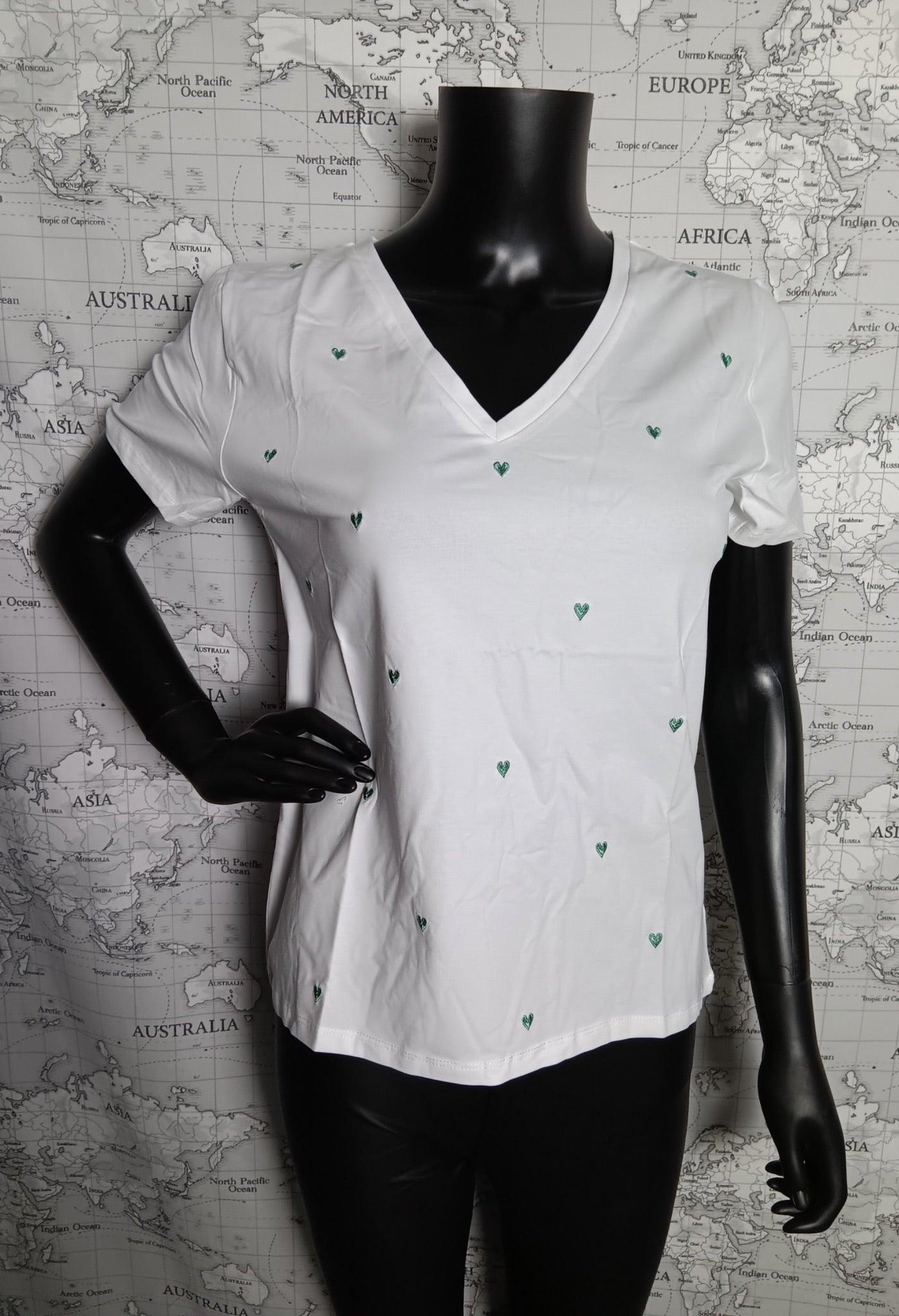 T-shirt blanc à col en V avec petites broderies vertes en forme de cœurs, sur mannequin noir.