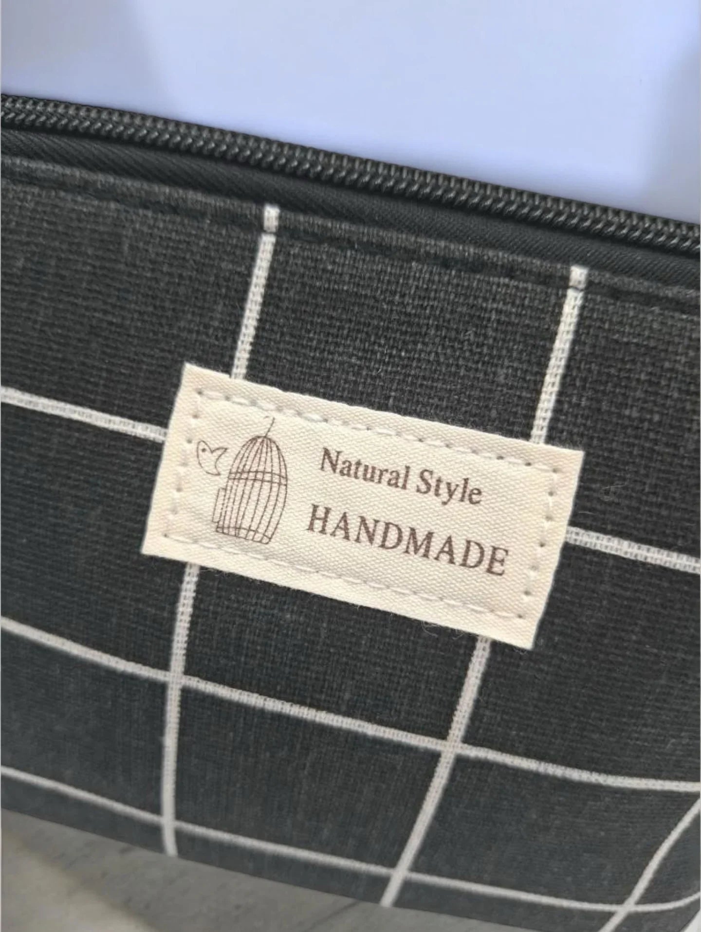 Trousse de toilette Le Petit Placard en coton à motifs à carreaux noirs et blancs, avec fermeture éclair visible.
