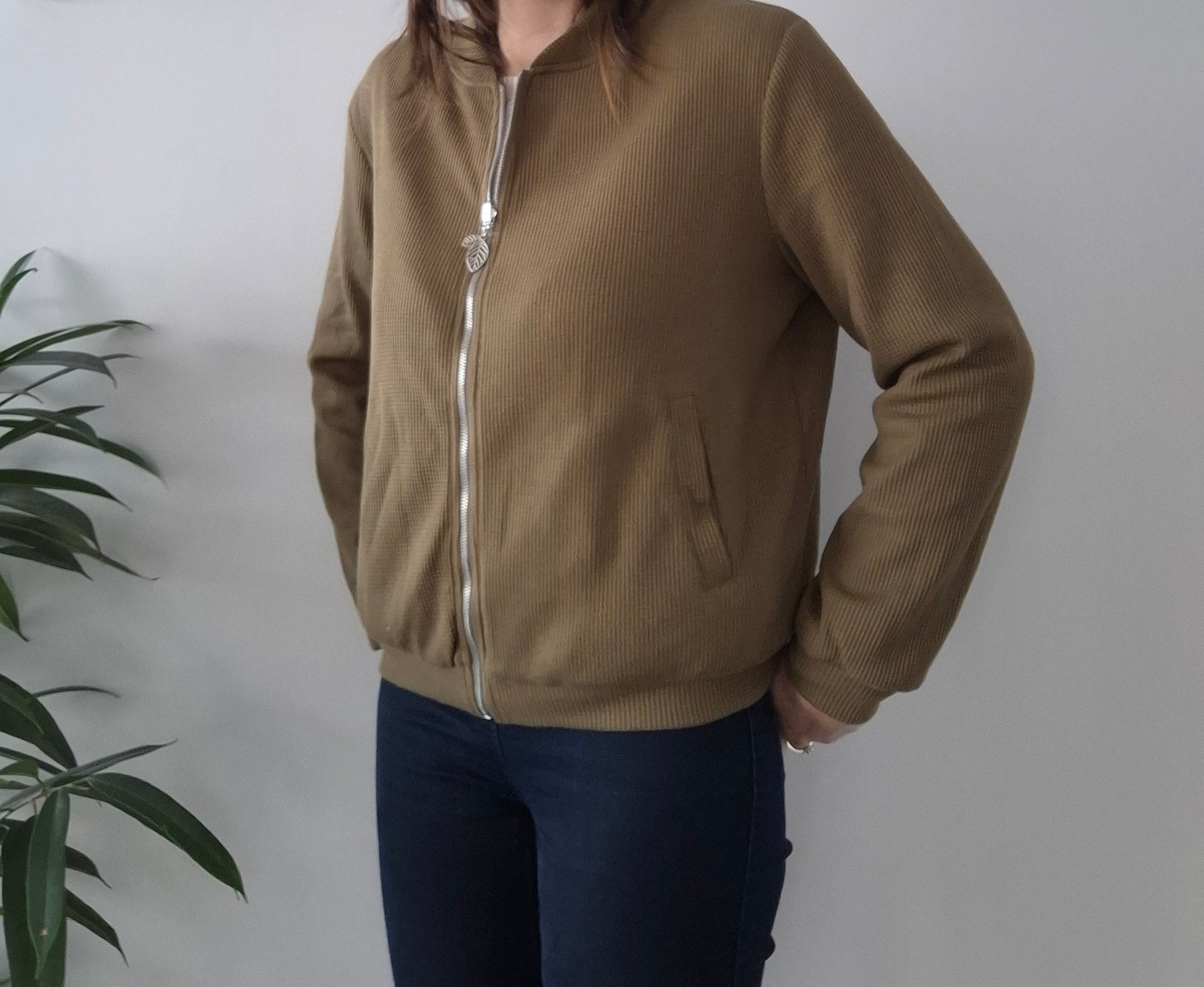 Woman wearing a khaki zip-up jacket from Le Petit Placard, casual fashion indoors