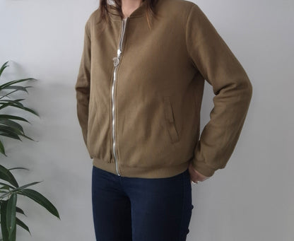 Woman wearing a khaki zip-up jacket from Le Petit Placard, casual fashion indoors