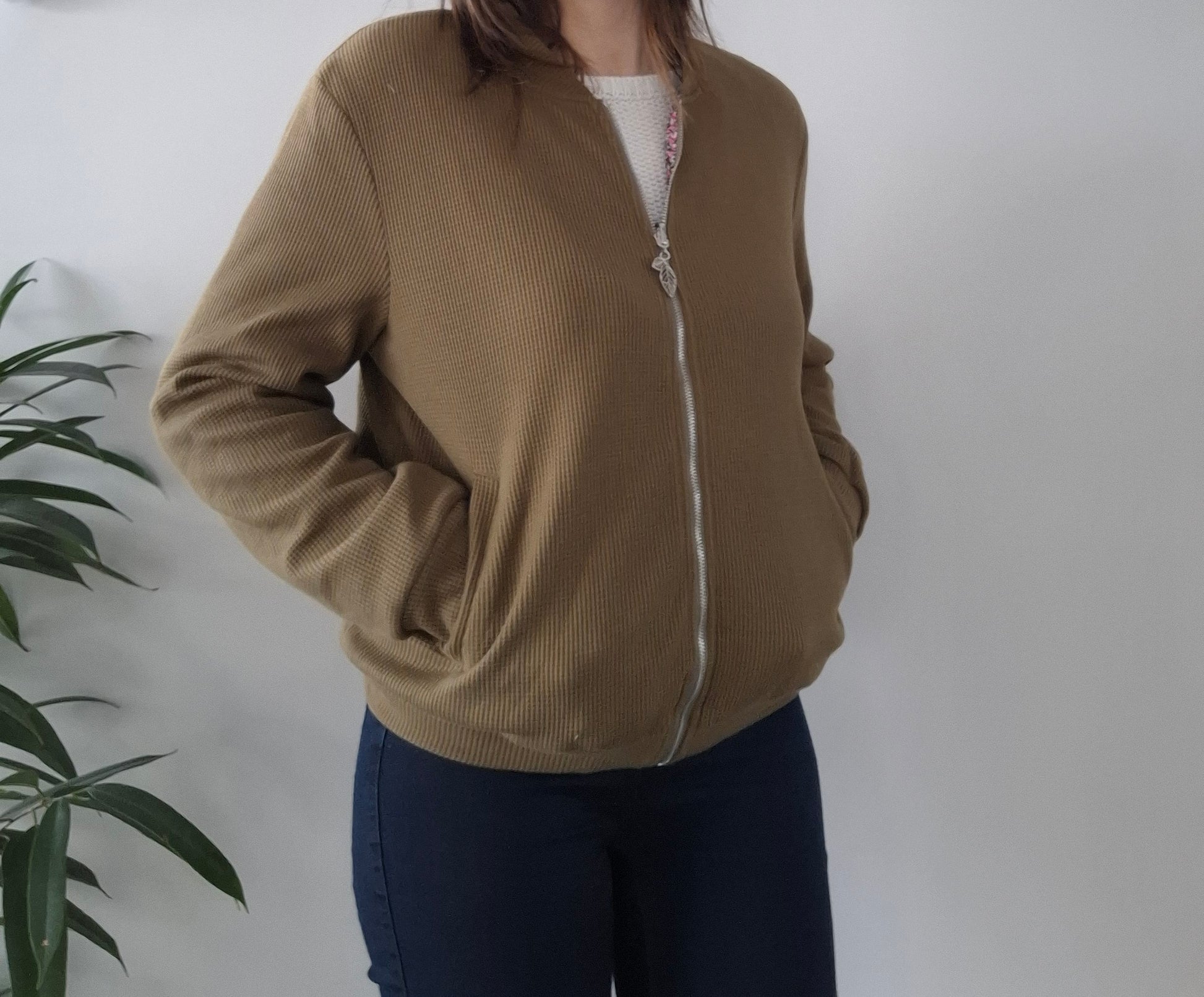 Woman wearing a brown zip-up jacket, casual fashion from Le Petit Placard, against white wall
