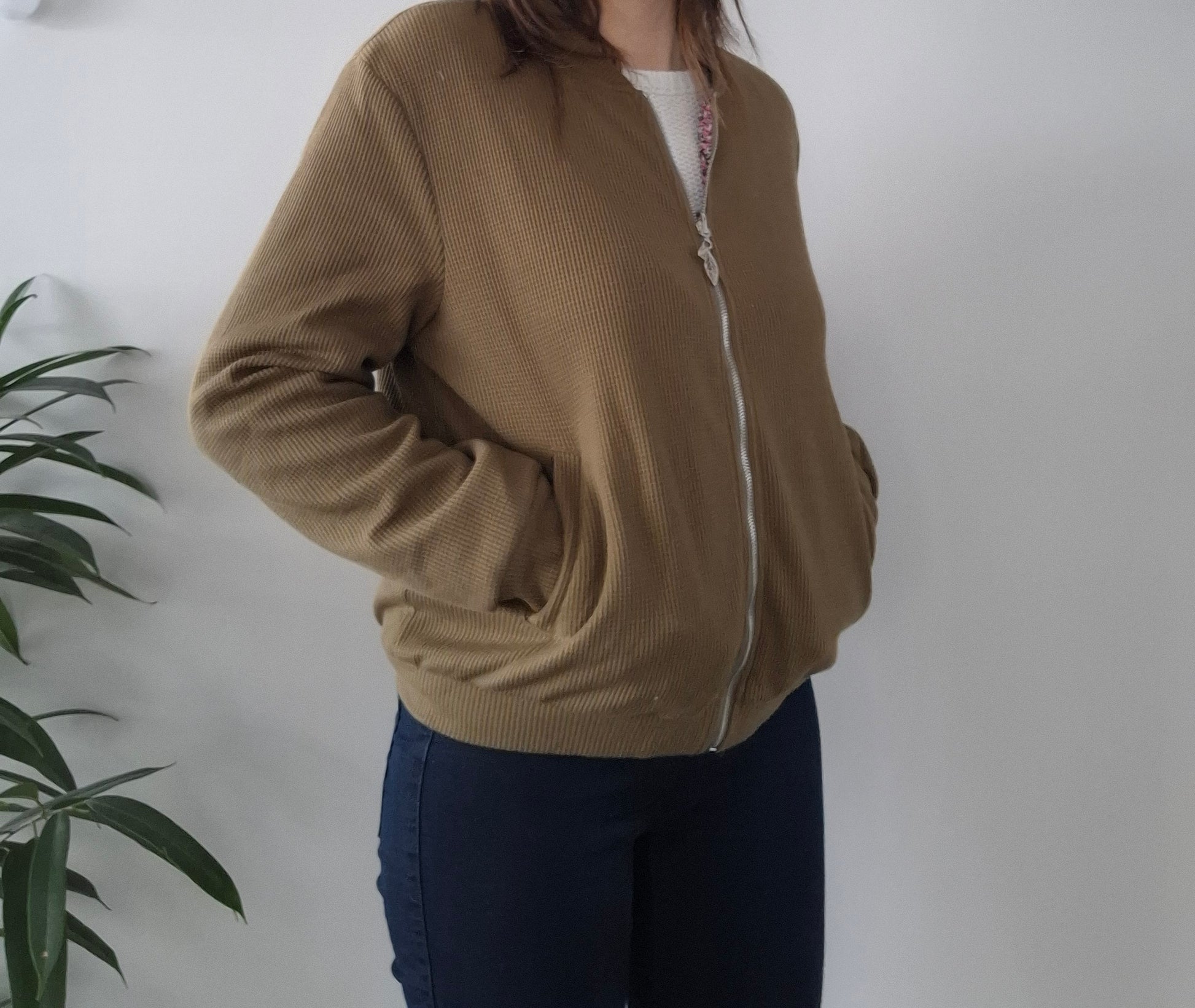 Woman wearing a beige zip-up jacket, casual style from Le Petit Placard, neutral background