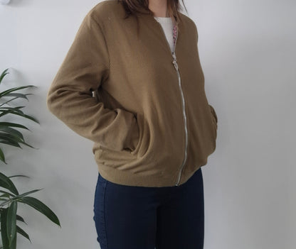 Woman wearing a beige zip-up jacket, casual style from Le Petit Placard, neutral background